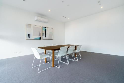 a conference room with a wooden table and white chairs at Urban Apt in Phillip 9mins to Canberra Hospital - Hosted by Canstay in Phillip