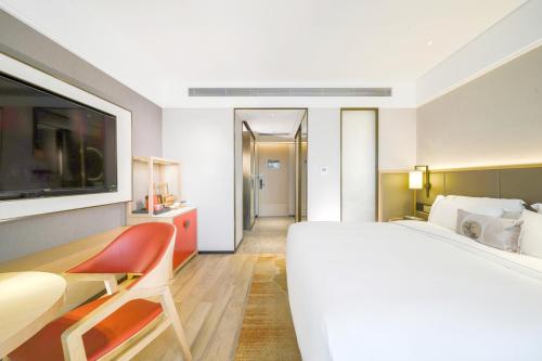 a bedroom with a large white bed and a tv at Nanning Vientiane City Convention and Exhibition Center Yicheng Hotel in Nanning