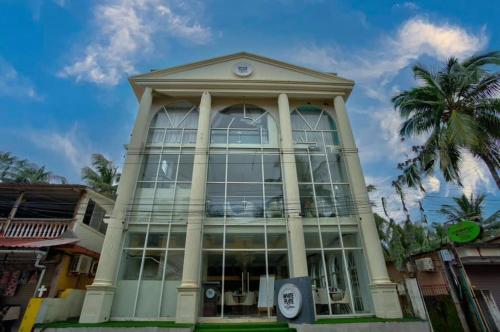 a large building with large windows and a palm tree at Candolim Beach White Residency in Baga
