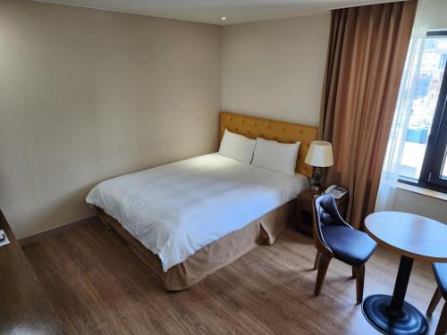 a bedroom with a bed and a table and a chair at Hotel Haema in Jeju