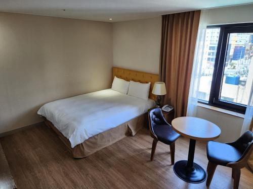 a hotel room with a bed and a table and chairs at Hotel Haema in Jeju