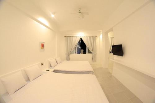 a white room with two beds and a window at Coron Bluewave Hotel in Coron