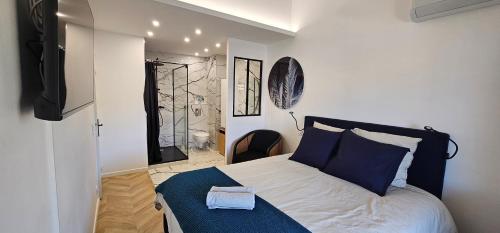 une chambre avec un lit avec des oreillers bleus et une télévision dans l'établissement L'exquis 800m plage et croisette, à Cannes