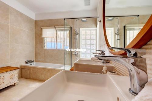 un bagno con un lavandino, una vasca e uno specchio di Villa Vénus - classée 4 étoiles - Piscine et vue mer - Saint-Gilles les Bains a L'Ermitage-Les-Bains