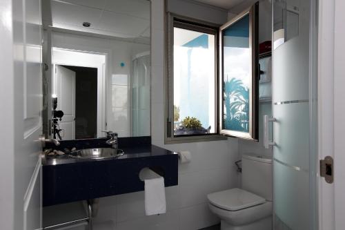 ein Badezimmer mit Waschbecken und Toilette und einem Fenster in der Unterkunft Gran Lugar -Mar Azul in La Manga del Mar Menor