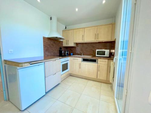 une cuisine avec des appareils électroménagers blancs et des armoires en bois dans l'établissement PGH N38 - Centre-Ville, Port avec Parking Privé, à La Grande Motte