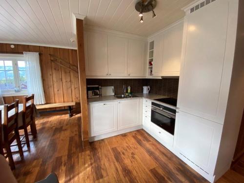 a kitchen with white cabinets and a wooden floor at Ruud Tun in Hafjell