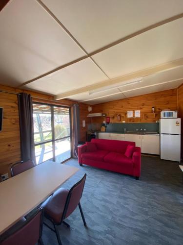 a living room with a red couch and a table at Anglers Reach Lakeside Village in Anglers Reach