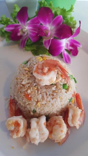 a white plate with shrimp and rice and purple flowers at Kasithorn Apartment's & Hotel in Phetchabun