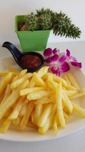a plate of french fries on a plate with a spoon at Kasithorn Apartment's & Hotel in Phetchabun