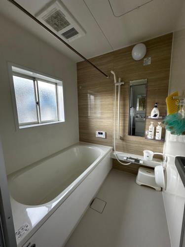 a bathroom with a tub and a sink and a mirror at Urasa Cottage @ Snow Countryside in Minami Uonuma