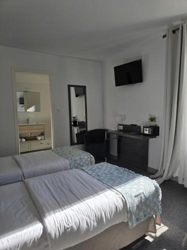 a hotel room with two beds and a television at Hôtel L'Alsace in Narbonne