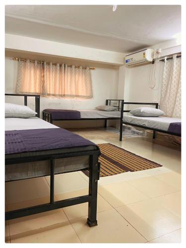 a room with three beds and a rug at Zion Backpackers Hostel in Guwahati