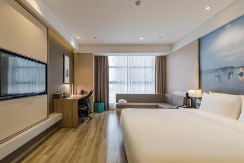 a hotel room with a large bed and a desk at Atour Hotel Hangzhou Binjiang Jiangling Road in Hangzhou