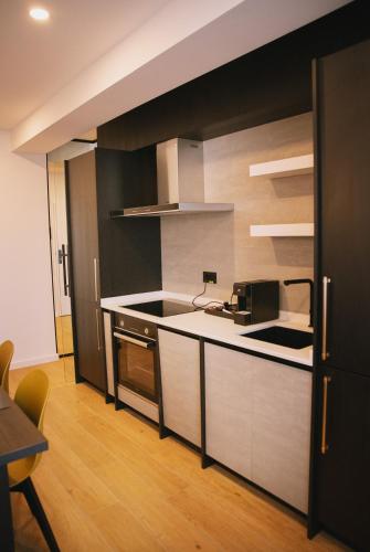 a kitchen with white cabinets and a black wall at Electra Aparthotel in Rădăuţi