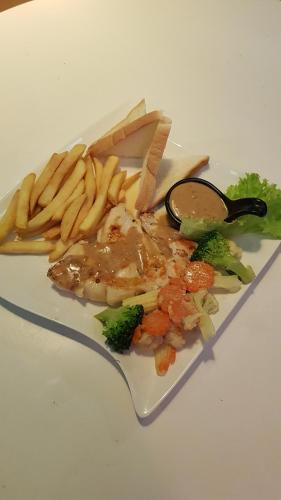 a plate of food with meat and fries and broccoli at Kasithorn Apartment's & Hotel in Phetchabun