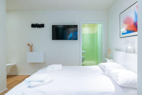 a white bedroom with a bed and a tv at HITrental Riesbach Apartments in Zürich