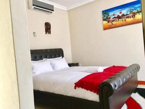 a bedroom with a bed with a red blanket on it at Lamamie Suite Lodge in Thohoyandou