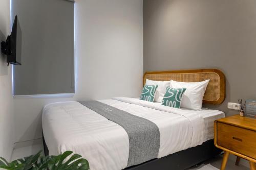 a bedroom with a bed with white sheets and blue pillows at Mono Coliving Pakis, Surabaya in Wonokitri 2