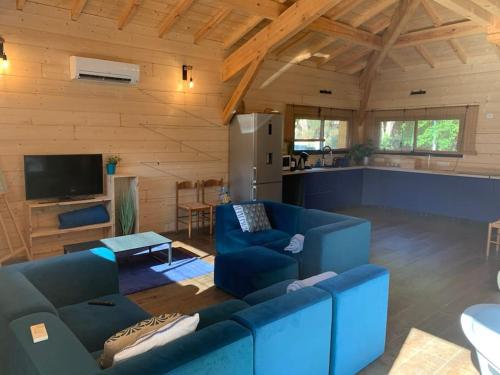 un salon avec des canapés bleus et une cuisine dans l'établissement Casa Lenha, Maison en bois avec 2 bassins, à Soustons