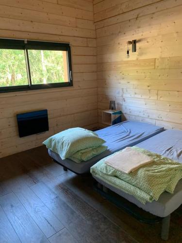 une chambre avec deux lits dans une cabane en rondins dans l'établissement Casa Lenha, Maison en bois avec 2 bassins, à Soustons