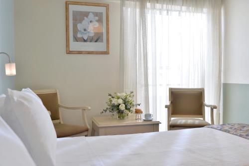 a bedroom with a bed and two chairs and a window at Airotel Parthenon in Athens