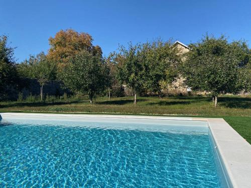 a swimming pool in front of a yard with trees at Chez Odette chambre Erable et Glycine in Esnoms-au-Val