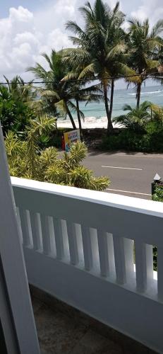 a balcony with a view of the beach and palm trees at White Surfing Beach Resort in Unawatuna