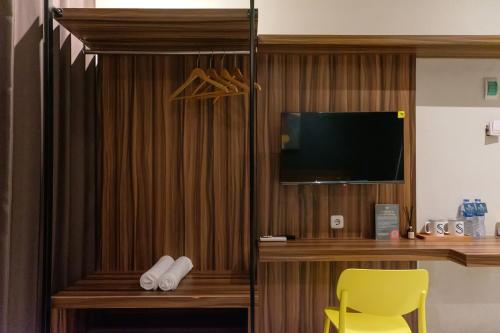 a room with a desk and a tv and a yellow chair at Mono Coliving Kencana, Surabaya in Gunungsan