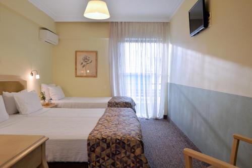 a hotel room with two beds and a window at Airotel Parthenon in Athens