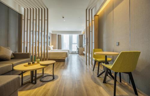 a hotel room with two tables and yellow chairs at Atour Hotel Hangzhou Binjiang Jiangling Road in Hangzhou