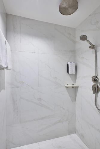 a bathroom with a shower with white marble walls at Sora Hotel Silom in Bangkok