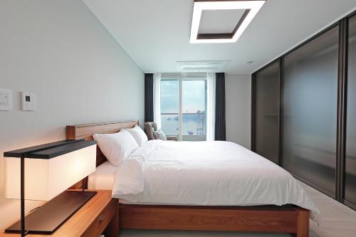 a bedroom with a white bed and a window at Elmomento Songdo in Busan