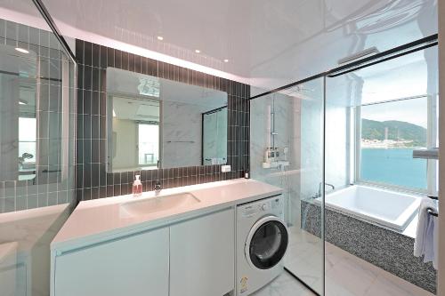 a bathroom with a sink and a washing machine at Elmomento Songdo in Busan
