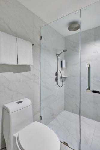 a white bathroom with a toilet and a shower at Sora Hotel Silom in Bangkok