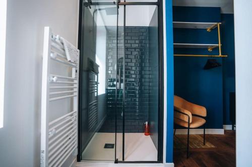 - une porte de douche en verre dans une chambre avec une chaise dans l'établissement Le Blue Bering - Confort & Design - Climatisation, à Châteauroux