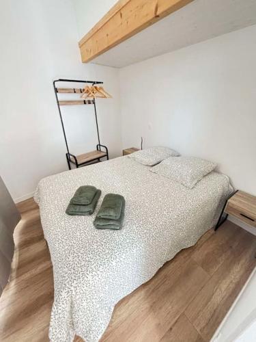 - une chambre avec un lit et 2 serviettes vertes dans l'établissement Le Moulin, appartement rénové au coeur d'Arago, à Les Sables-dʼOlonne