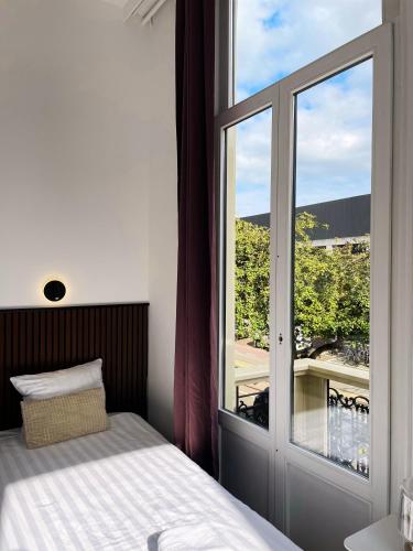a bedroom with a bed and a large window at Hotel Plantage in Amsterdam