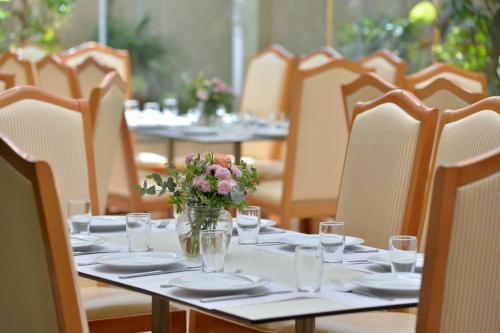 a table with plates and a vase of flowers on it at Airotel Parthenon in Athens