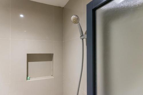 una ducha con cabezal de ducha en un baño en Mono Coliving Ngagel, Surabaya, en Menurpumpungan