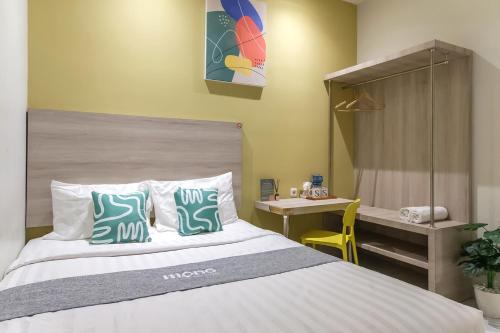 Un dormitorio con una cama con almohadas azules y blancas. en Mono Coliving Ngagel, Surabaya, en Menurpumpungan