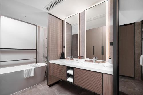a bathroom with two sinks and a tub and a mirror at Grand Mercure Wuhan Hanyang in Wuhan