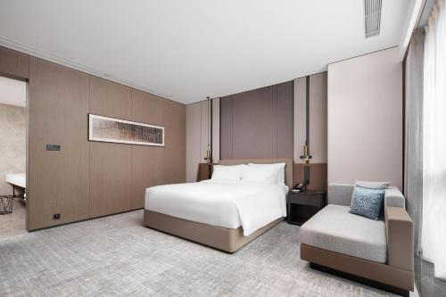 a hotel room with a bed and a chair at Grand Mercure Wuhan Hanyang in Wuhan
