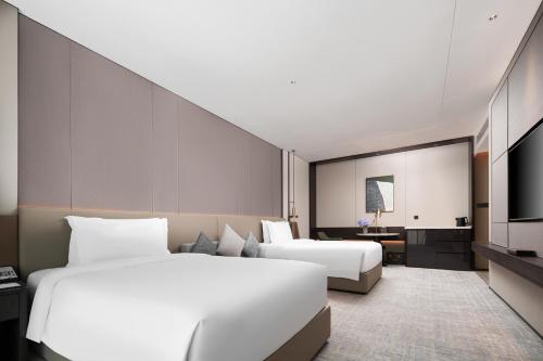 a hotel room with two beds and a tv at Grand Mercure Wuhan Hanyang in Wuhan