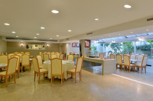 a dining room with tables and chairs in a restaurant at Airotel Parthenon in Athens