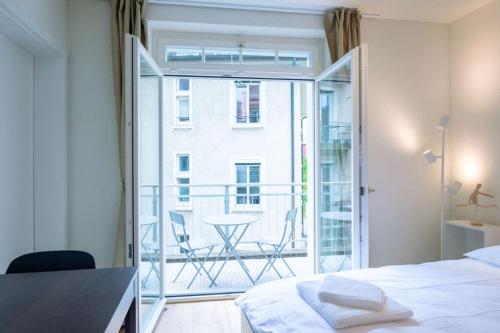 a bedroom with a bed and a balcony with a table at HITrental Riesbach Apartments in Zürich