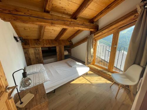 une chambre avec un lit, une chaise et une fenêtre dans l'établissement Face aux 3 vallées, à Bozel