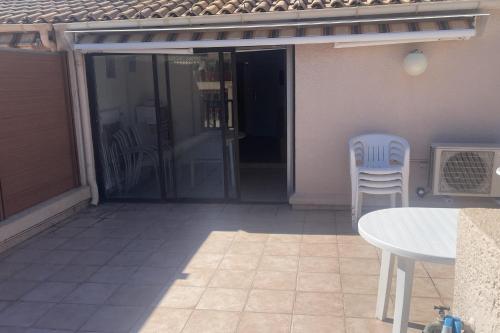 Une porte ouverte s'ouvre sur une terrasse avec une table et des chaises. dans l'établissement Bright flat with large terrace, à Bandol