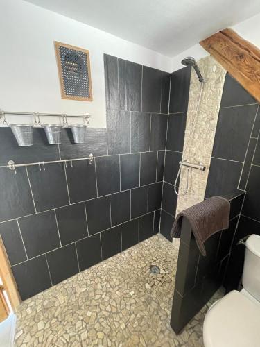 La salle de bains est pourvue d'une douche avec du carrelage noir. dans l'établissement Face aux 3 vallées, à Bozel