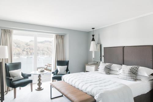 Un dormitorio con una cama y dos sillas y una ventana. en Dart Marina Hotel, en Dartmouth